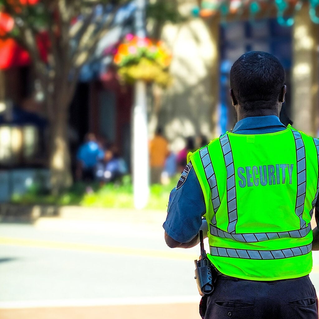 Security officer in bright vest monitoring premises, showcasing professional presence for safety and patrol services.
