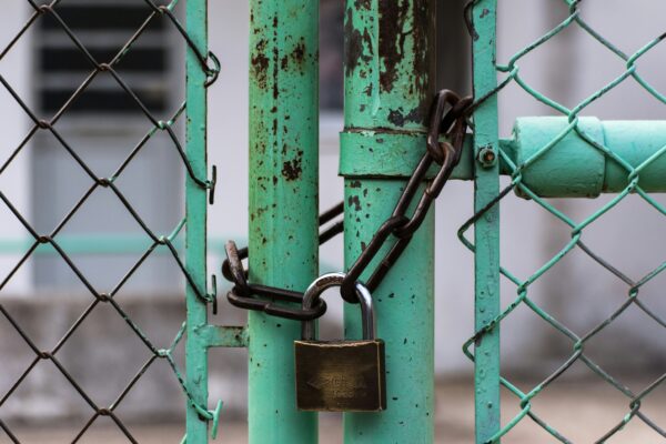 Photo of a green gate locked with a chain and padlock