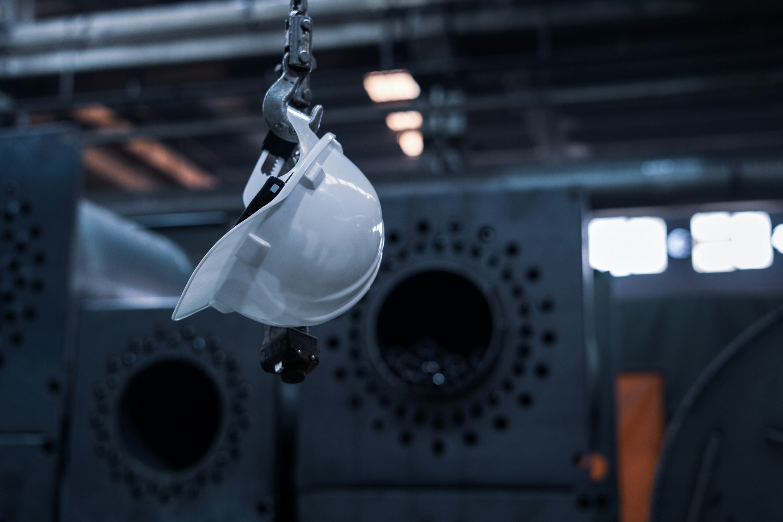 Photo of a safety helmet hanging from a chain inside of a factory